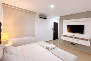 A hotel room with a bed, a TV mounted on the wall, a window, and an air conditioning unit. - Elegant Apartment free parking near US Consulate (Guayaquil)