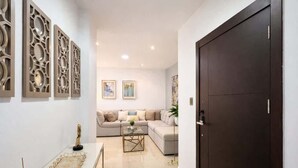 A modern living room with a sofa, coffee table, decorative wall panels, and a dark wooden door. - Elegant Apartment free parking near US Consulate (Guayaquil)