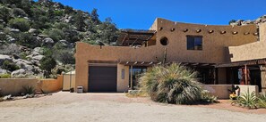 Un bâtiment de style désertique avec un garage, entouré de cactus et de rochers.