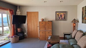 Una sala de estar con sofá, mesa de centro, televisor, chimenea y ventana con cortinas.
