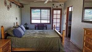 Un dormitorio con cama, cómoda de madera, mesita de noche y escritorio con silla.