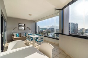 Un balcon doté d’un espace repas, d’un canapé et offrant une vue sur le paysage urbain et les montagnes.