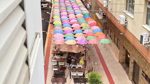 Ein Hotelkorridor mit Reihen bunter Regenschirme, Sitzgelegenheiten im Freien und einem sichtbaren Restaurant.