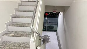 Eine Treppe mit weißen Wänden und Granitstufen, die zu einer Tür führt, auf der 'SAÍDA' steht.