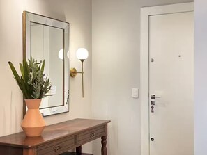 Ein Badezimmer mit einem Holzkosmetikschrank, einem Spiegel mit goldener Rahmung, einer Topfpflanze und einer Tür mit Schloss.