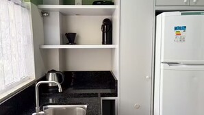 Una cocina equipada con un lavaplatos, una cafetera, un hervidor y un refrigerador.