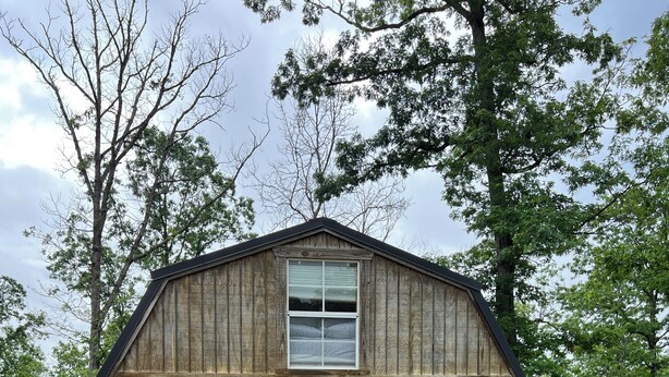 Eine Hütte mit Veranda, zwei gelbe Stühle und ein Bett, das durch das Fenster zu sehen ist.
