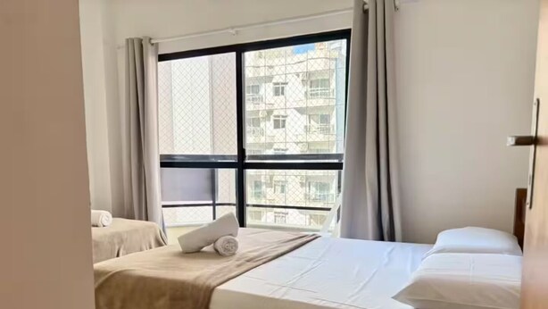 Een hotelkamer met een bed, een klein tafeltje en een raam met uitzicht op gebouwen.