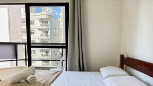 Een hotelkamer met een bed, een raam met uitzicht op gebouwen, en een gordijn.