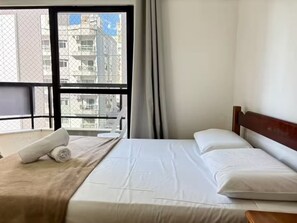 Ein Hotelzimmer mit Bett, Fenster und Blick auf Gebäude.