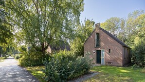 Une petite maison en briques avec un toit en pente, une porte d’entrée et une fenêtre.