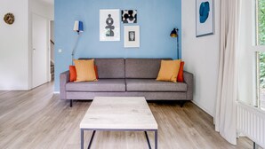 A living room with a grey sofa, a white coffee table, and blue walls. - Relaxing Forest Escape for 6 (Ewijk)