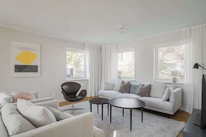 A modern living room with a sofa, armchair, coffee table, and a TV. - Lakefront Villa in Saltsjöbaden near Stockholm (Saltsjöbaden)
