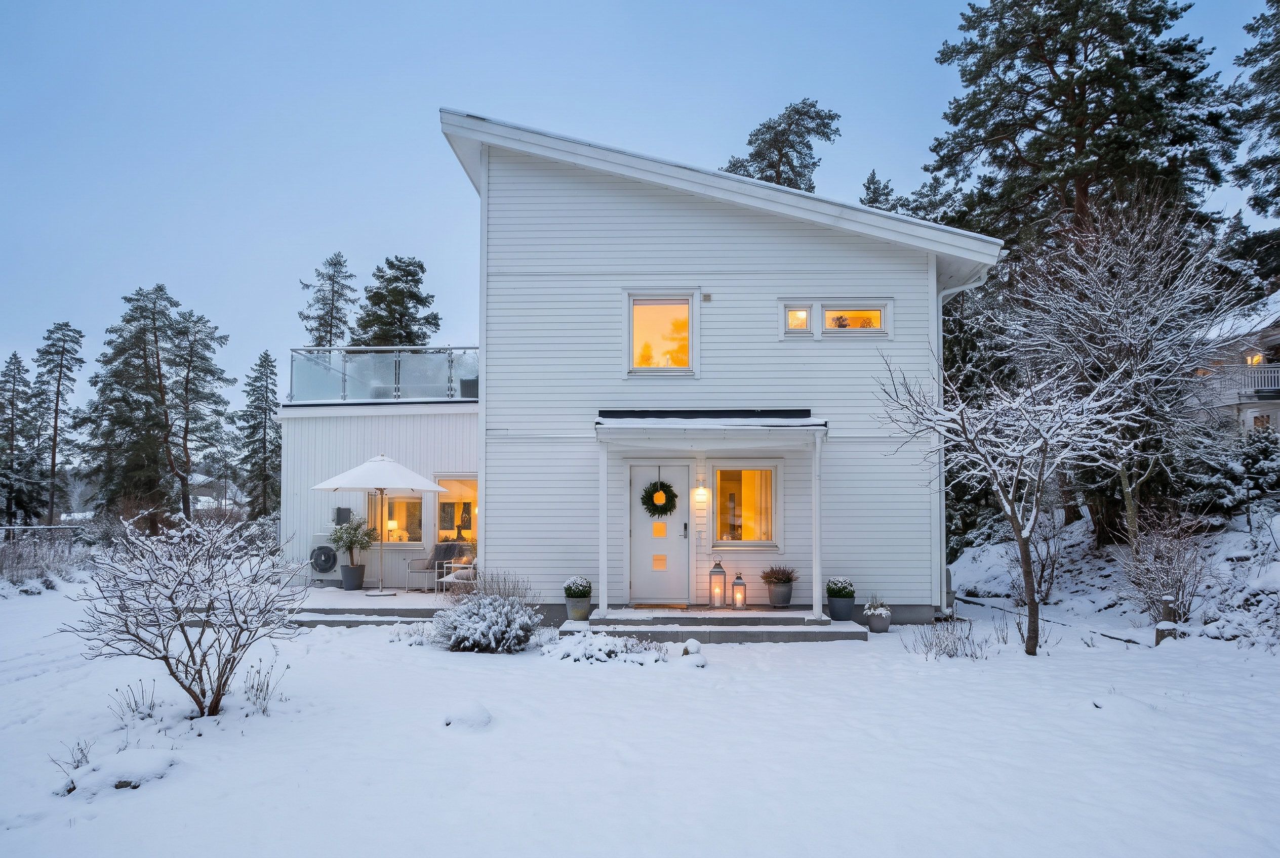 Ein zweigeschossiges Haus mit Balkon und Veranda, vor verschneiter Landschaft.
