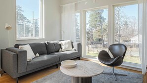 Un salon moderne avec un canapé gris, une table ronde et une chaise noire.