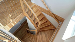 Un escalier en bois avec une rampe en métal, un plancher en bois et un mur blanc.