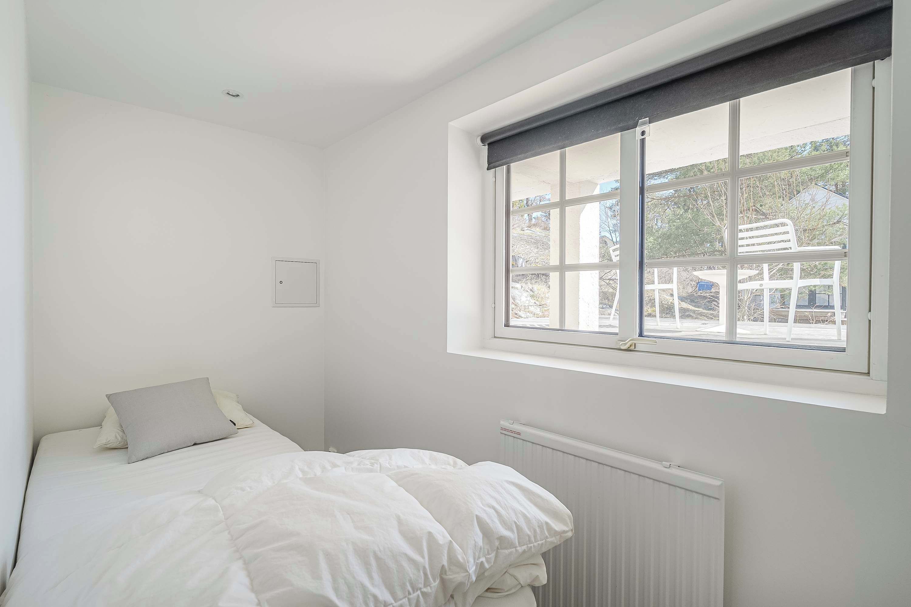 Et soveværelse med seng, vindue og radiator.