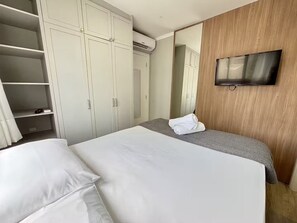 A hotel room with a bed, a TV, a wardrobe, and a mirror. - Oceanfront near the Ferris Wheel - 1 Bedroom (Balneário Camboriú)