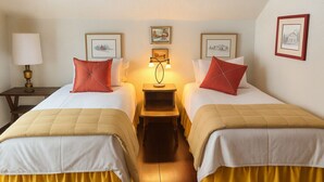 A hotel room with two beds, a nightstand with a lamp, and framed pictures on the wall. - a Vermont mountain adventure cabin (Cambridge)