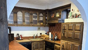 A kitchen with wooden cabinets, a central island, and a tiled backsplash. - a Vermont mountain adventure cabin (Cambridge)