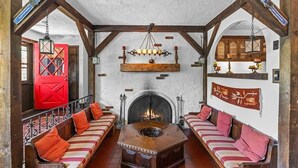 A rustic room with a fireplace, wooden beams, and striped sofas with red cushions. - a Vermont mountain adventure cabin (Cambridge)