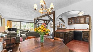 A spacious living room with a wooden dining table, a chandelier, and a kitchen with wooden cabinets and a tiled backsplash. - a Vermont mountain adventure cabin (Cambridge)