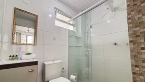 Een badkamer met toilet, wastafel, spiegel en douchecabine.