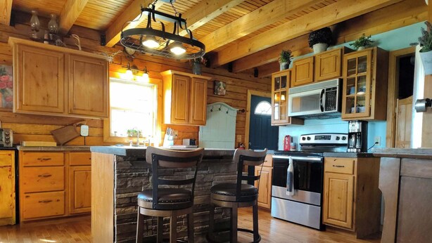 A rustic kitchen with wooden cabinets, a stone island, and a stainless steel stove. - 37 acres, fishing, hunting, golf course nearby, rustic feel, hiking, near town. (Pocahontas)