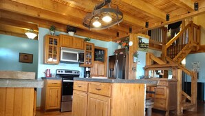 A wooden kitchen with a central island, wooden cabinets, a microwave, stove, refrigerator, and a staircase. - 37 acres, fishing, hunting, golf course nearby, rustic feel, hiking, near town. (Pocahontas)