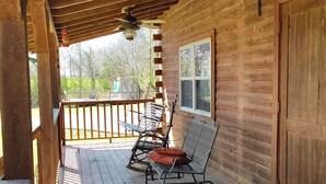A wooden deck with a covered area, two rocking chairs, a metal grill, and a view of the outdoors. - 37 acres, fishing, hunting, golf course nearby, rustic feel, hiking, near town. (Pocahontas)