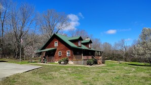 A log cabin with a green roof, a porch, and a small deck. - 37 acres, fishing, hunting, golf course nearby, rustic feel, hiking, near town. (Pocahontas)