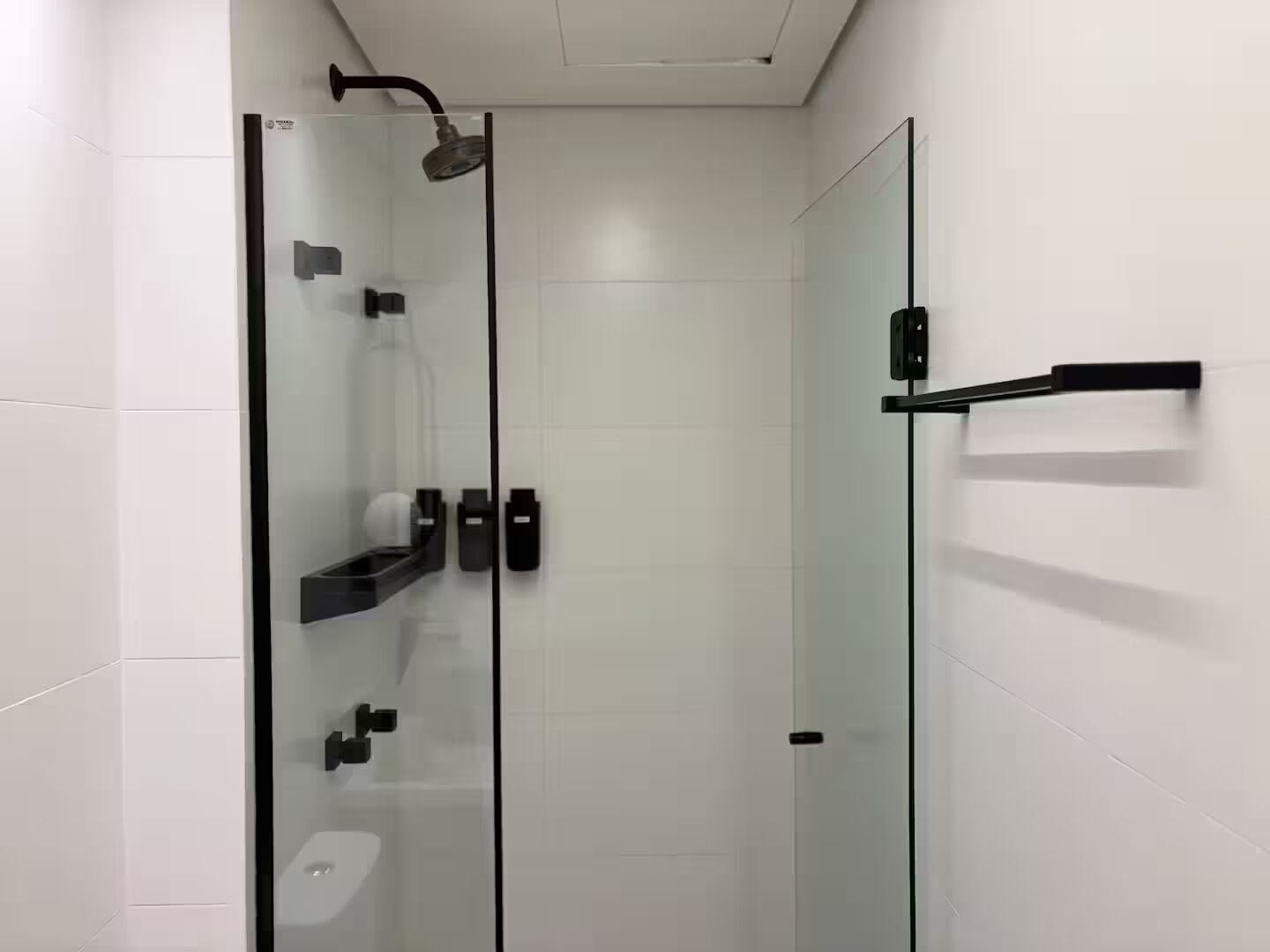A modern bathroom with a glass shower enclosure, a toilet, and a sink with a black faucet.