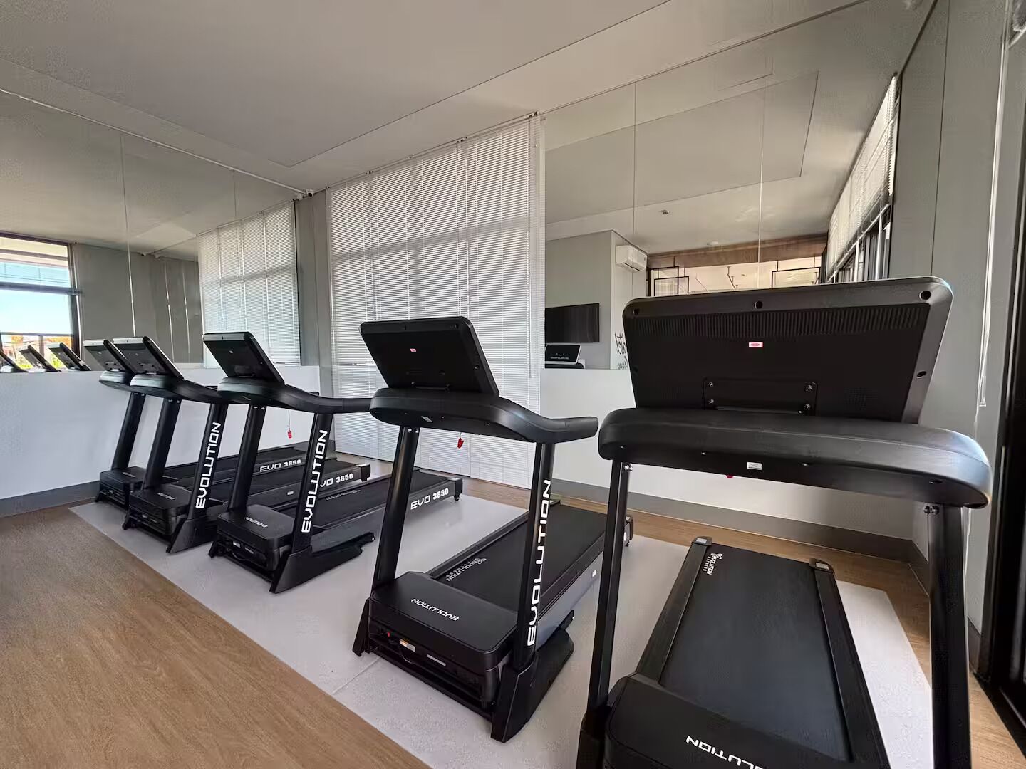 Un gimnasio con cintas de correr, una banca y una televisión.