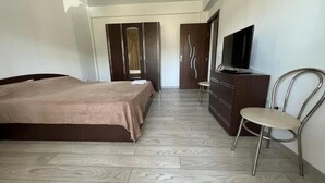 Een hotelkamer met een bed, een televisie, een kaptafel en een stoel.