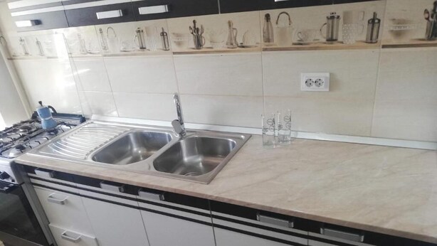 Een keuken met een dubbele spoelbak, roestvrijstalen apparatuur en een betegelde achterwand.