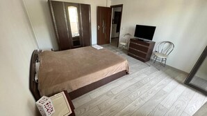 Een slaapkamer met een bed, een televisie, een dressoir en een stoel.