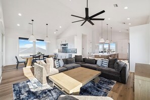 A spacious living area with a large sectional sofa, a wooden coffee table, and pendant lighting. - Beach Escape with Pool w/Game Room (Port St. Joe)