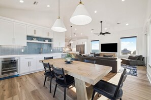 A modern kitchen with white cabinets, a wooden dining table, and pendant lighting. - Beach Escape with Pool w/Game Room (Port St. Joe)