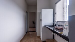A narrow kitchen with a refrigerator, a sink, and a window.
