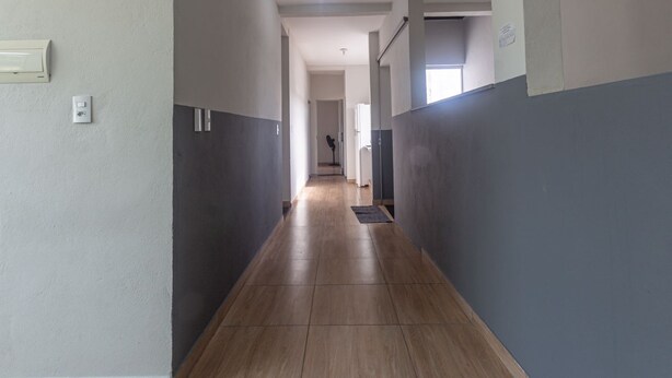 A hallway with a wooden floor, grey walls, and a ceiling light.