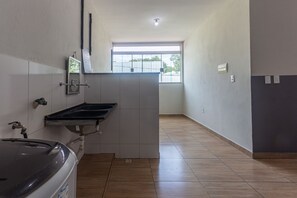 A narrow hallway with a tiled floor, a window with a view of trees, and a sink with a mirror. - Apartamento 4 Quartos com Wi-fi e Garagem (Para de Minas)