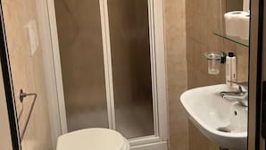 A bathroom with a toilet, a glass shower enclosure, and a sink with a mirror. - ines downtown (Rome)