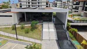 A modern building with a covered walkway, outdoor seating, and a pool area. - Cais Eco Residencia by Manta e BHL (Ipojuca)