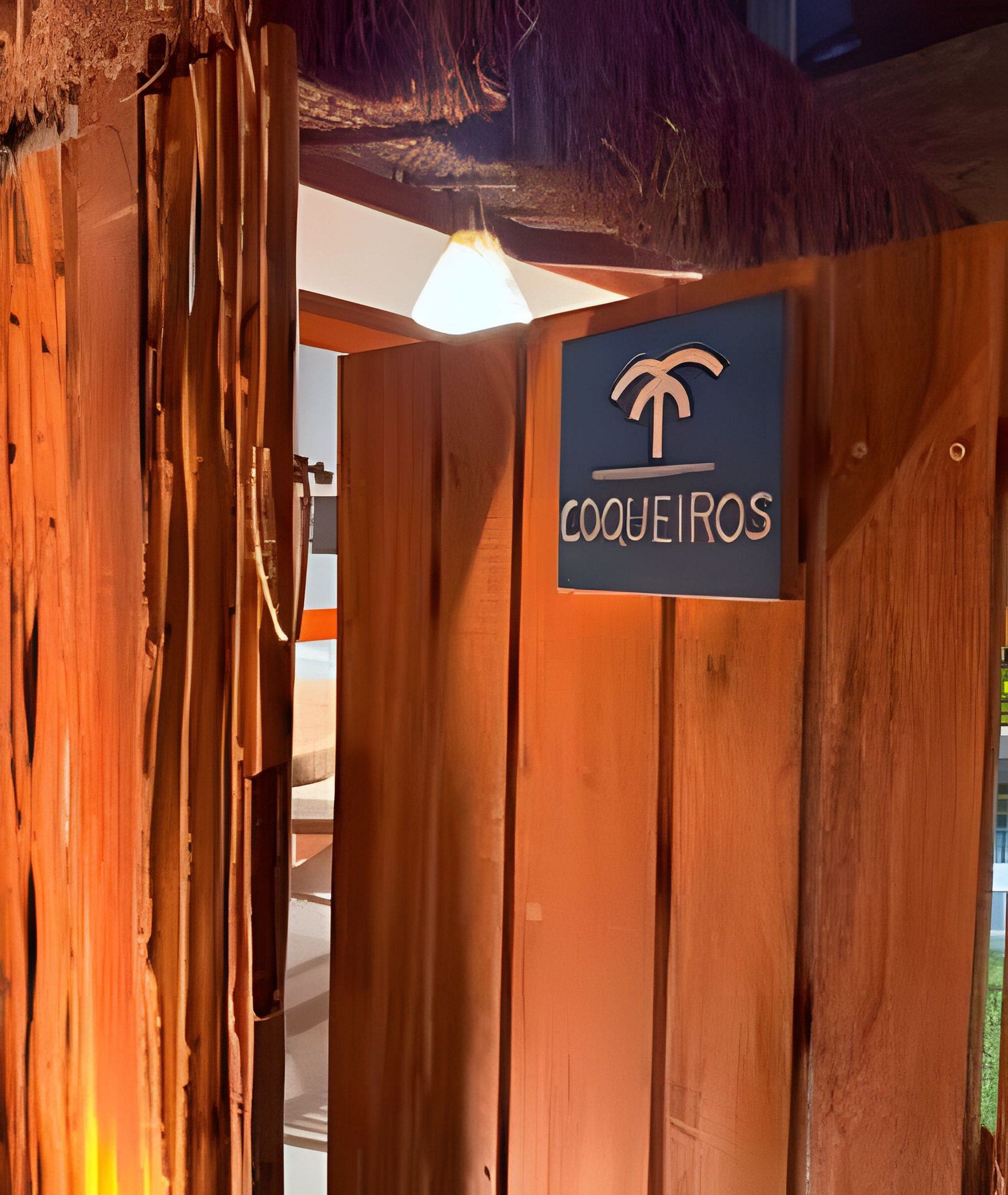 A wooden gate with a sign reading 'COQUEIROS' and a palm tree symbol.
