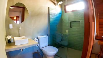 Un baño con inodoro, lavabo, espejo y cabina de ducha de vidrio.