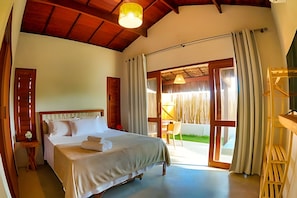 Quarto com uma cama, mesa de cabeceira, abajur e vista para o exterior.