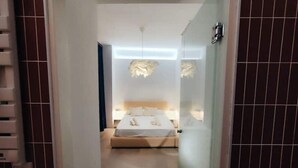 Une chambre d’hôtel avec un lit, des tables de chevet et un luminaire moderne.