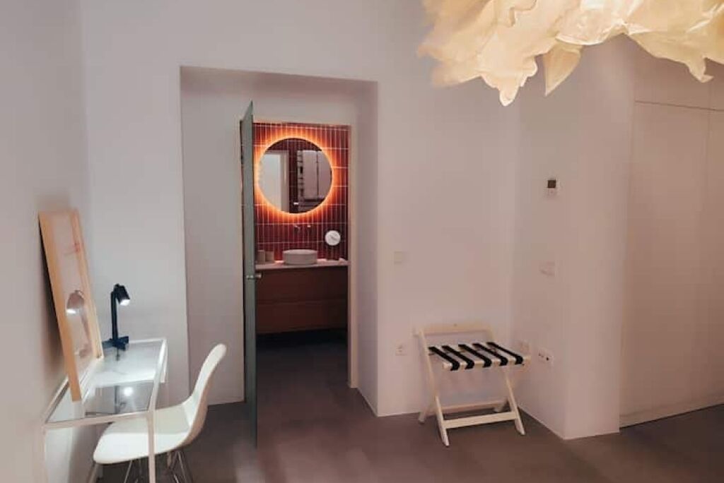 Ein modernes Badezimmer mit rundem Spiegel, Waschtisch und Duschbereich.