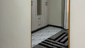 Quarto com guarda-roupa, espelho e tapete estampado.