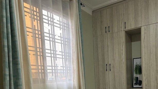 Quarto com cama, guarda-roupa e janela com cortinas.